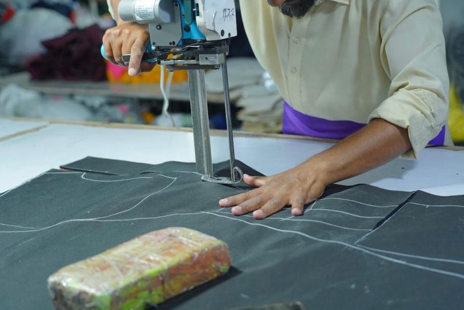 Worker cutting fabric with precision cutting machine